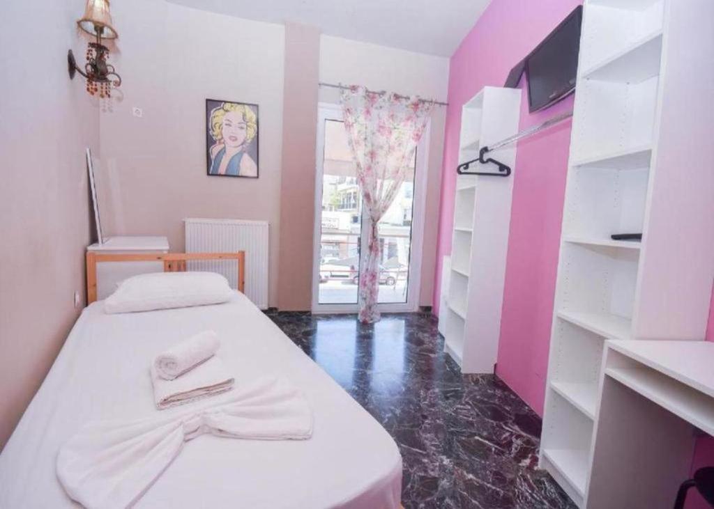 Kleines Zimmer mit einem Bett und einer rosa Wand in der Unterkunft Marilyn Athens Airport in Markopoulo