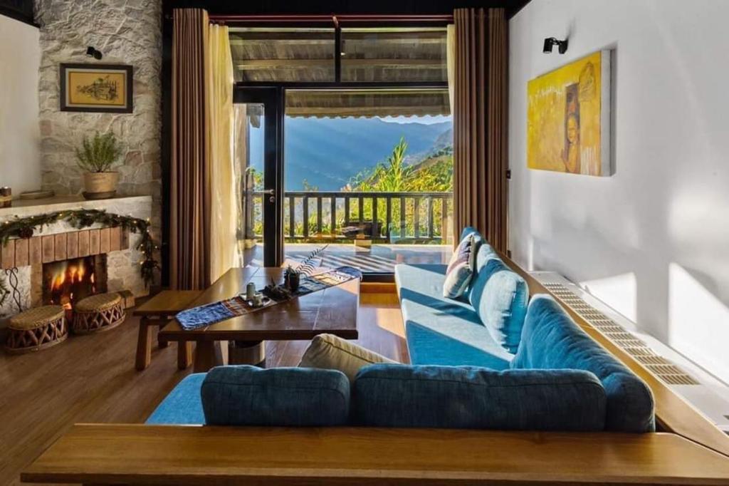 Heaven house sapa في لاو كاي: غرفة معيشة مع أريكة زرقاء ومدفأة