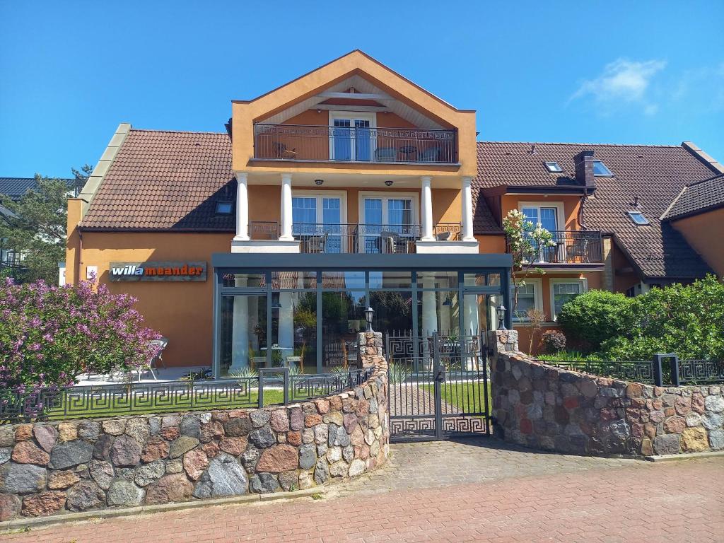 a large house with a stone fence in front of it at Willa Meander in Łeba