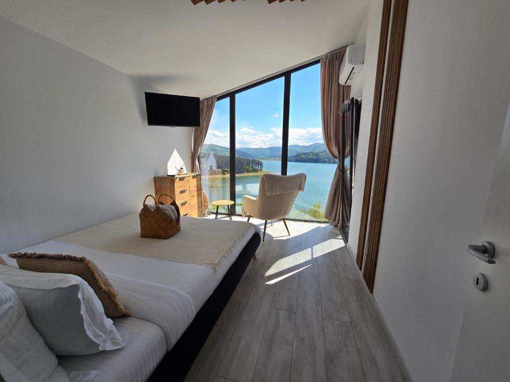 Schlafzimmer mit einem Bett und Blick auf das Wasser in der Unterkunft Moon Lake Bicaz in Buhalniţa