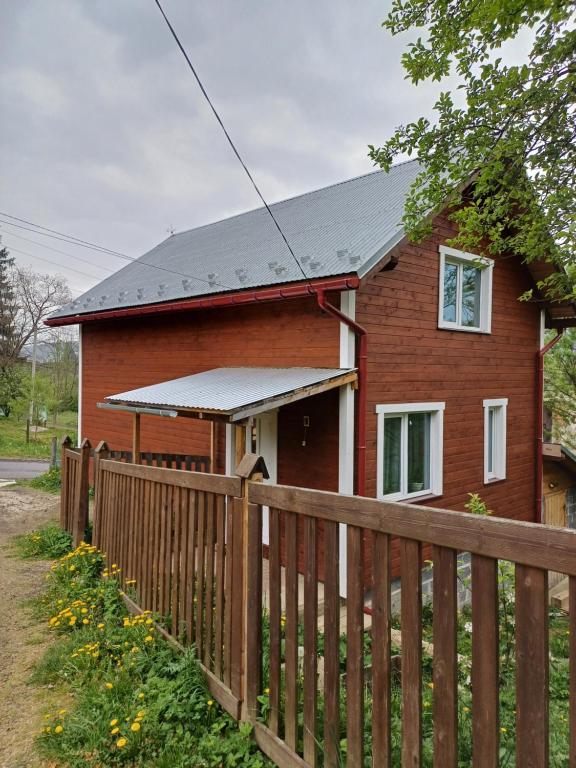 a red brick house with a wooden fence at Карпатський котедж Karpatian cottage in Vorokhta