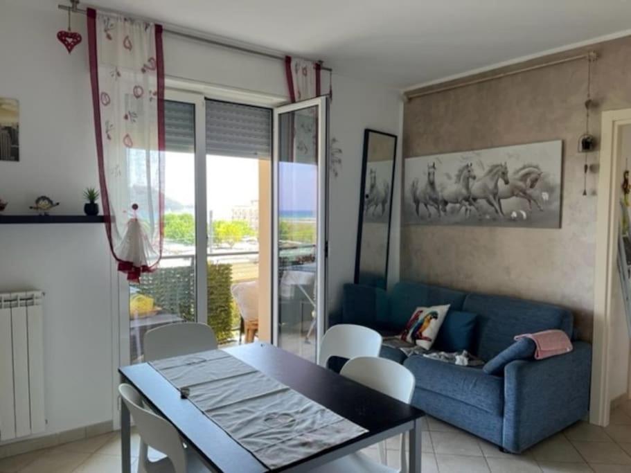 ein Wohnzimmer mit einem blauen Sofa, einem Tisch und Stühlen in der Unterkunft Appartamento vista mare in Albenga