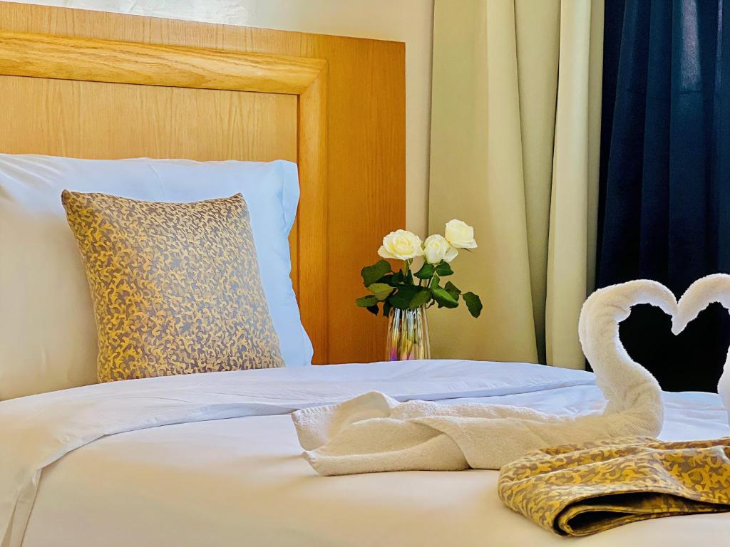 a bed with a swan towel and a vase with roses at Majliss Hotel Downtown in Rabat