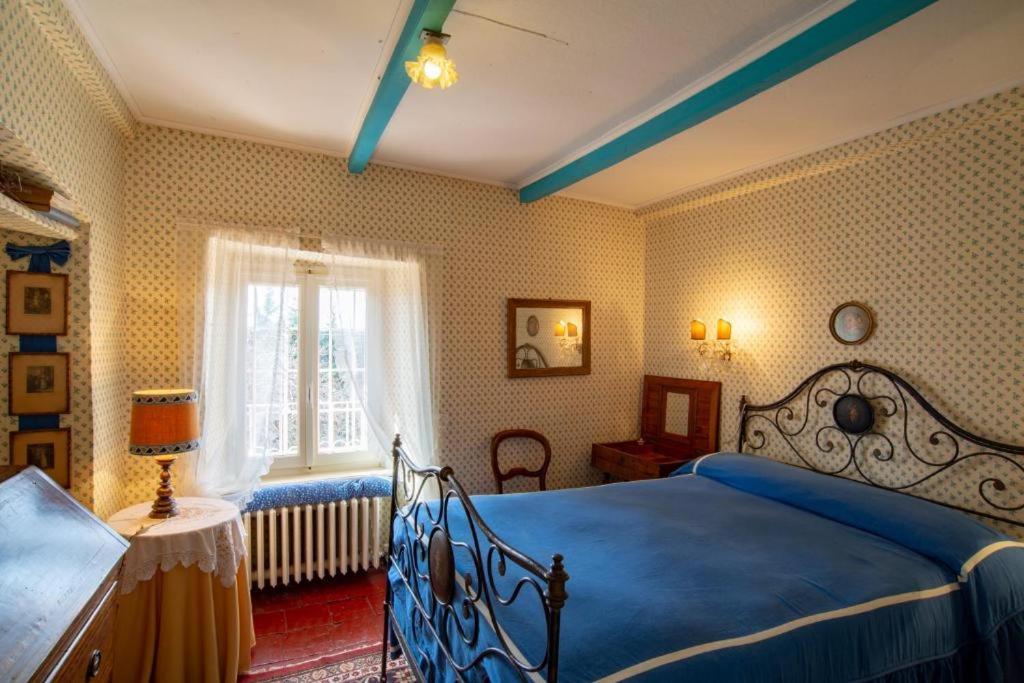 Un dormitorio con una cama azul y una ventana en La villa nel bosco, en Strona