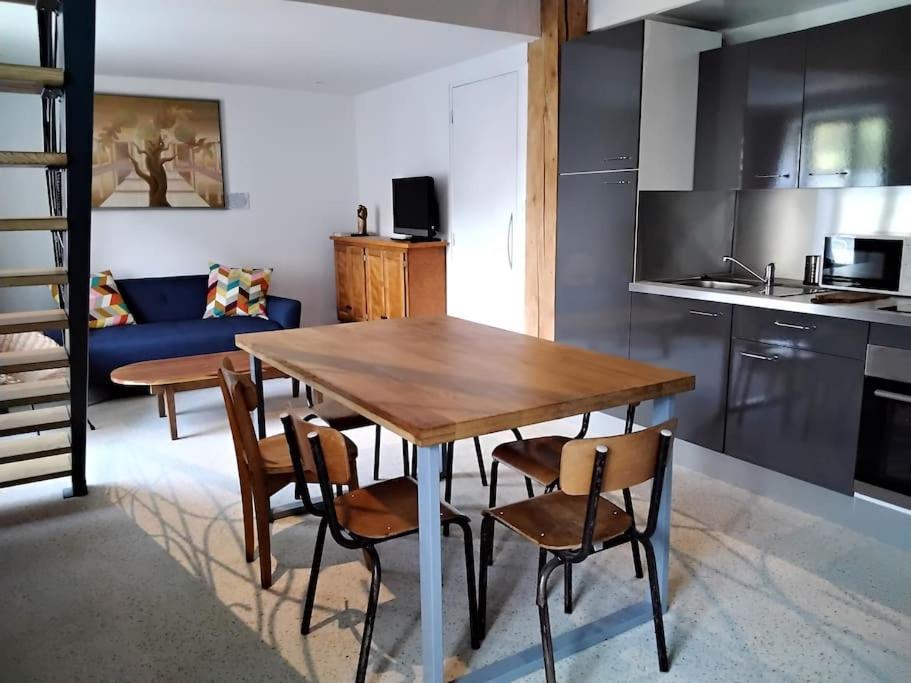 een keuken en eetkamer met een houten tafel en stoelen bij Gîte LE LOFT chez Judith et Neiges 