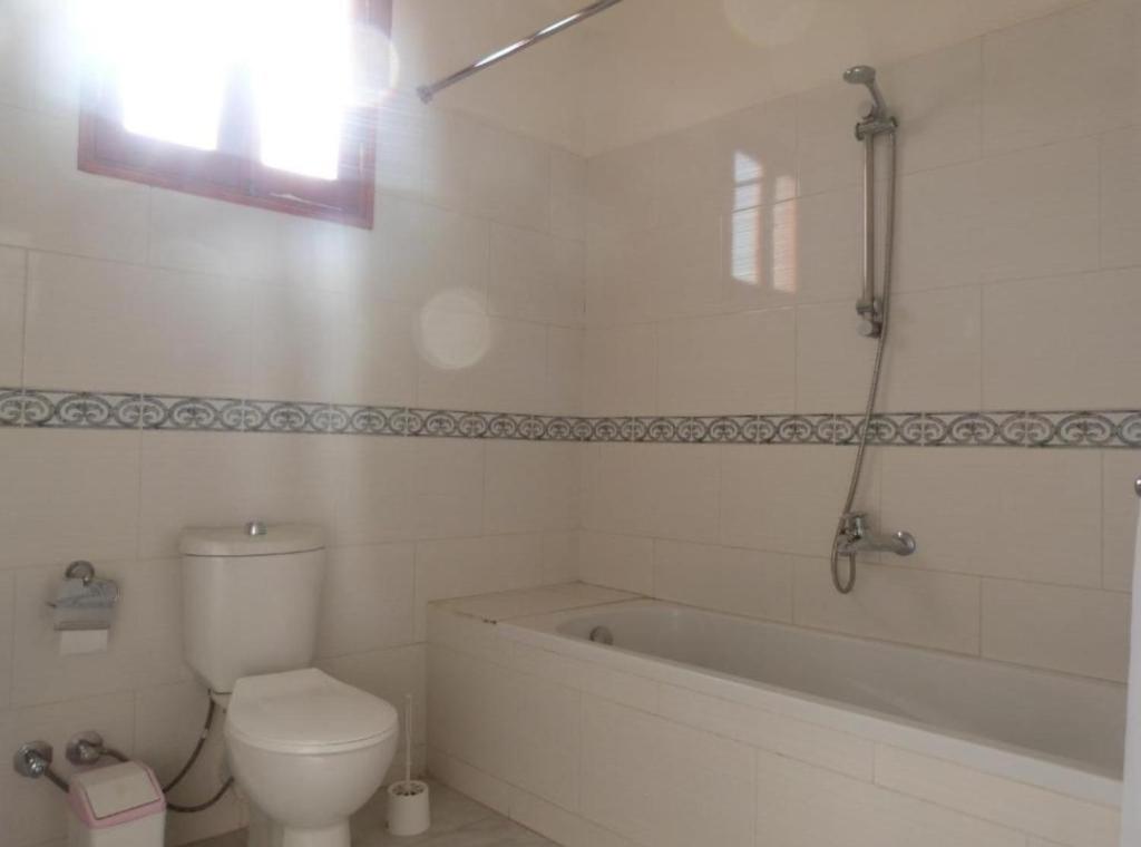a bathroom with a tub and a toilet and a bath tub at Mountain View Apartments Hotel in Al Aqālitah