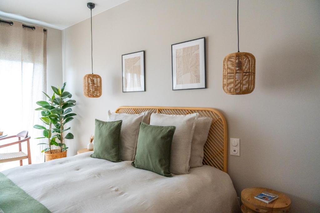 um quarto com uma cama com almofadas verdes em LE NID, superbe chambre d'hôtes em Mauves-sur-Loire