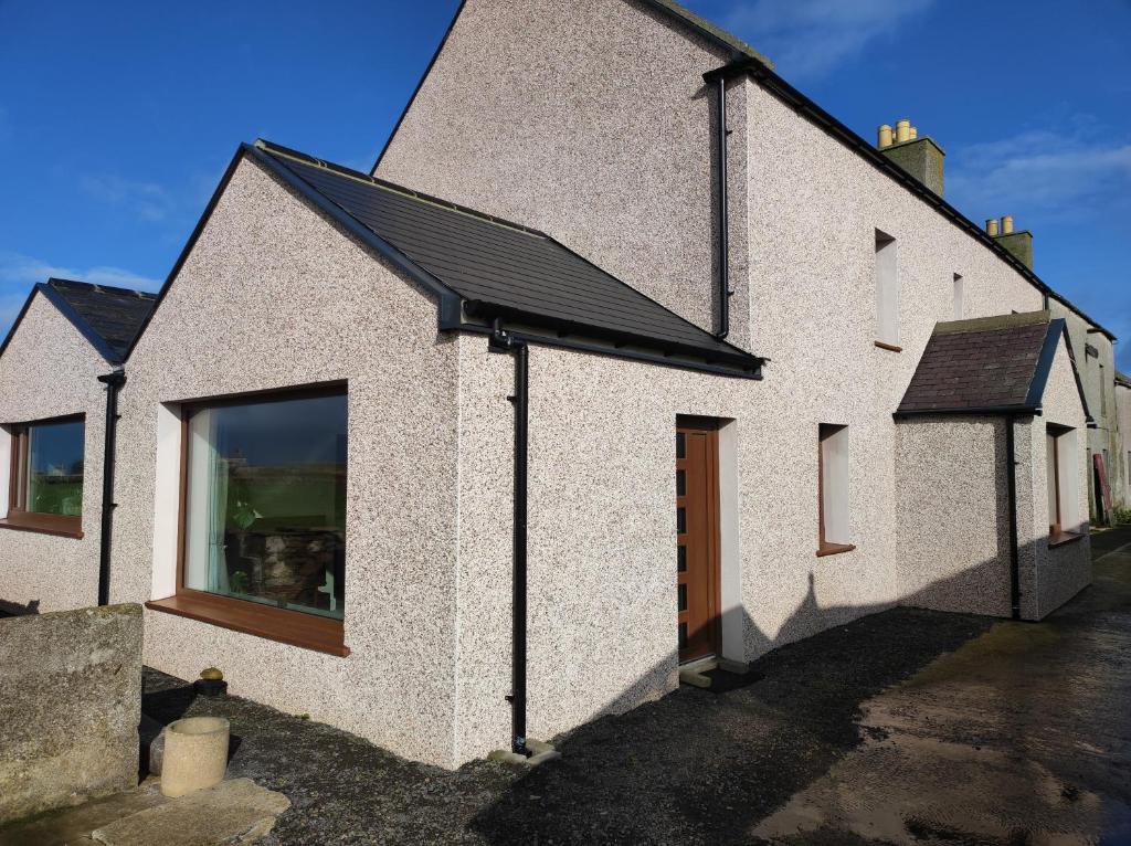 uma casa branca com um telhado preto em Castlehill, Sanday em Sanday