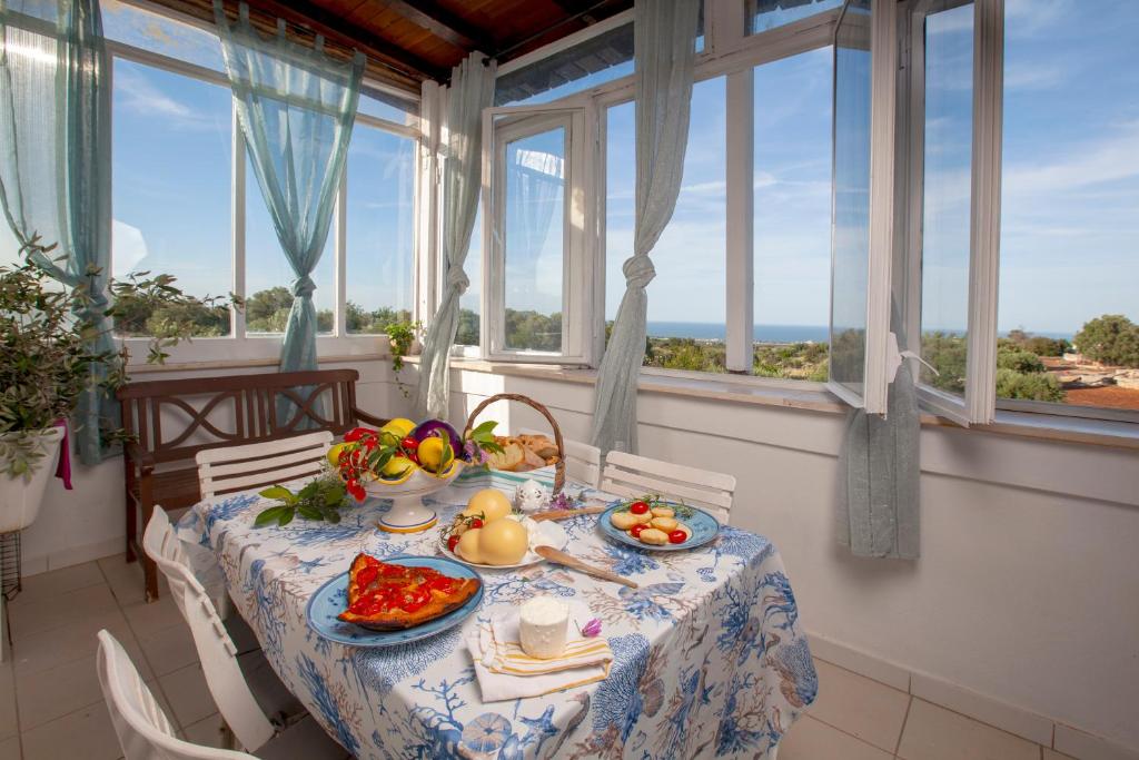einen Tisch mit Essen in einem Zimmer mit Fenstern in der Unterkunft Dimora Sanna Nature & Sea View in Polignano a Mare
