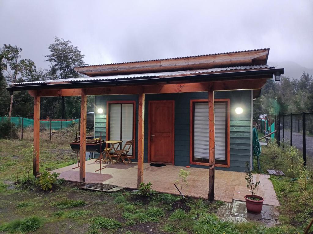 a small house with a porch and a table at Alojamiento Pamela in Coñaripe