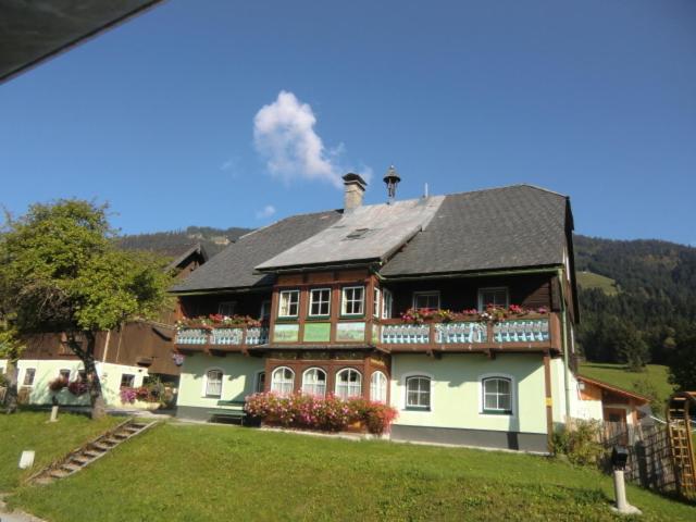 a large house with a black roof and flowers at Bunzbauernhof in Bad Mitterndorf