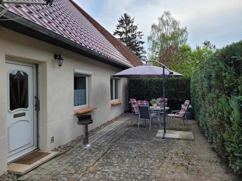 een patio met een tafel en stoelen en een parasol bij Ferienwohnung 500m zum See in Vollrathsruhe