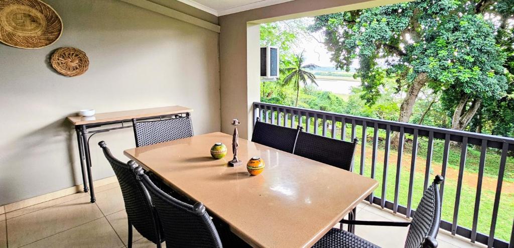 a table and chairs on a balcony with a large window at 6 The Bridge Self Catering Apartment in St Lucia