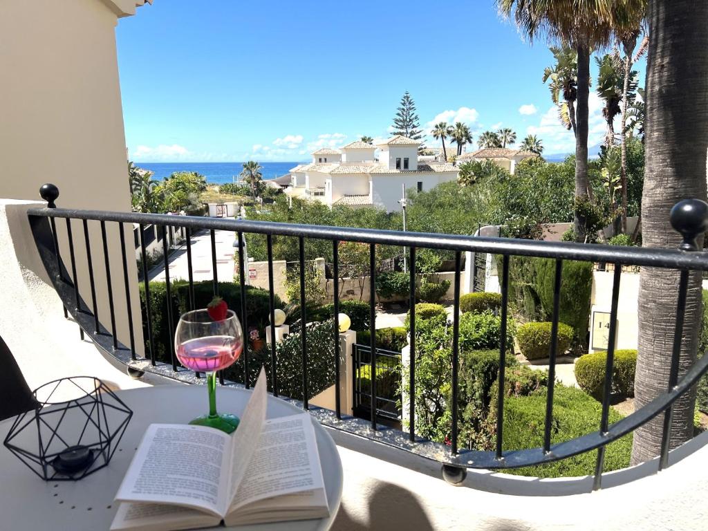 een tafel met een boek en een glas wijn bij STYLISH TOWNHOUSE IN BEACHFRONT COMPLEX in Marbella
