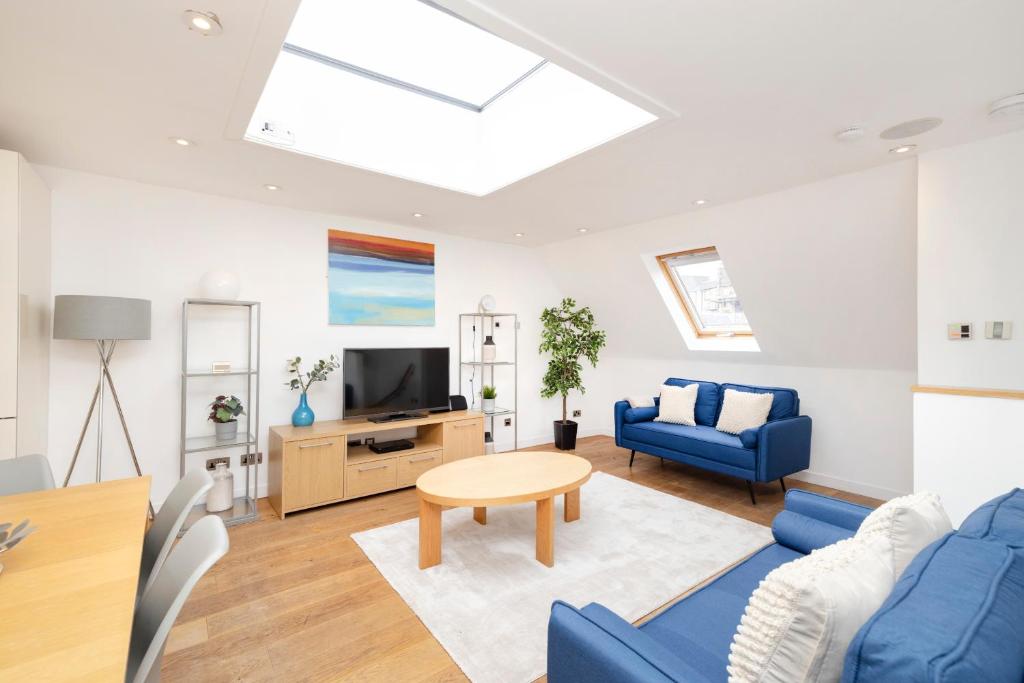 a living room with blue furniture and a skylight at JOIVY Superb Flats in the Heart of Edinburgh in Edinburgh