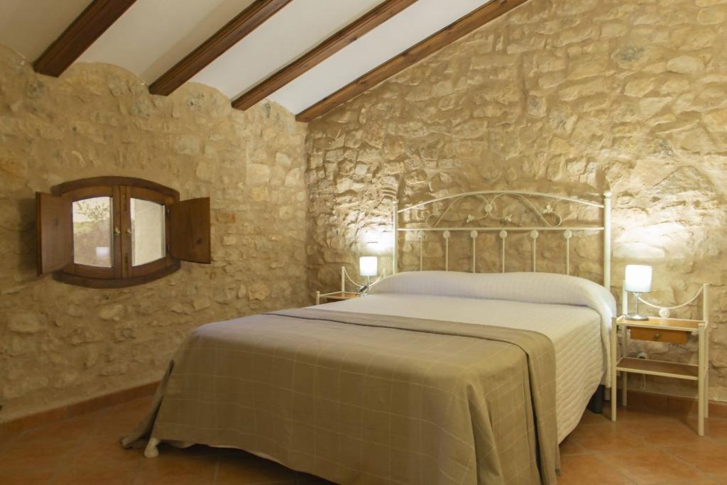 um quarto com uma cama numa parede de pedra em Masia Villa Pilar Valderrobres em Valderrobres