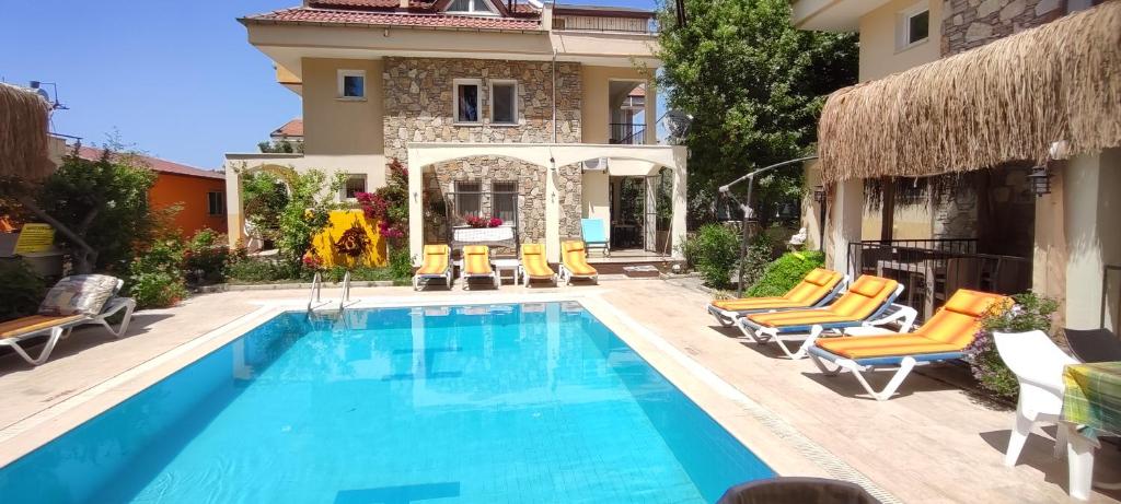 una piscina con sillas y una casa en çileks apart otel, en Fethiye