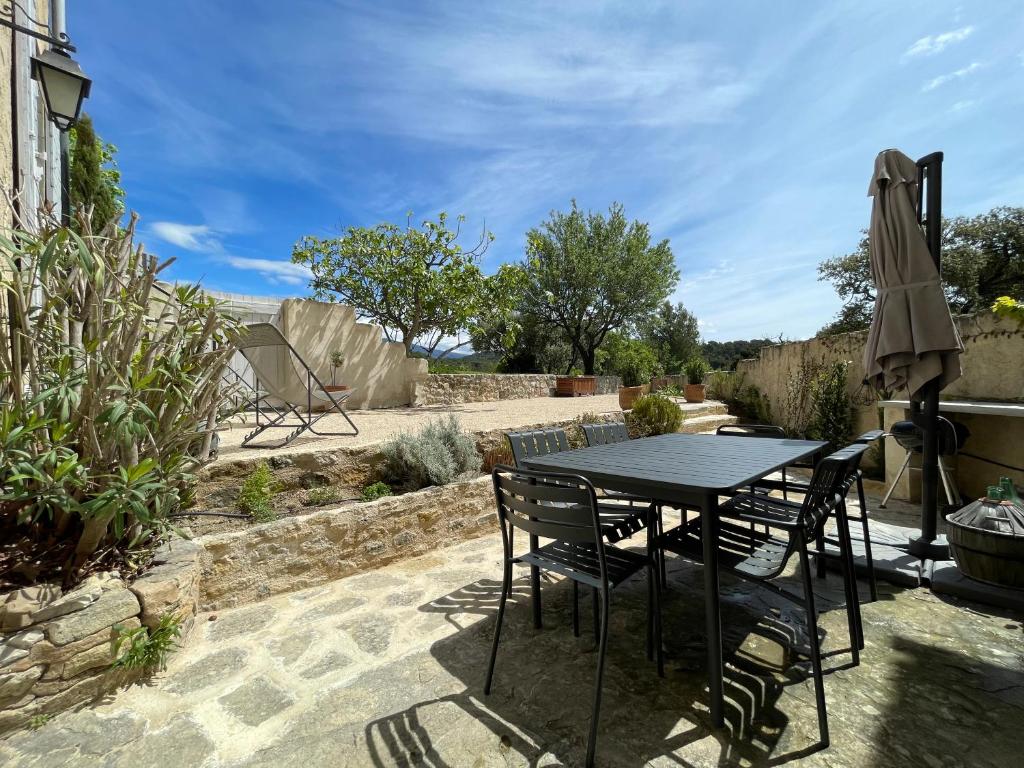 eine Terrasse mit einem Tisch, Stühlen und einem Sonnenschirm in der Unterkunft Magnifique maison Le Barroux in Le Barroux