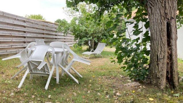2 chaises blanches et une table à côté d'un arbre dans l'établissement Au Pibolon des bois, à Saint-Hilaire-de-Riez