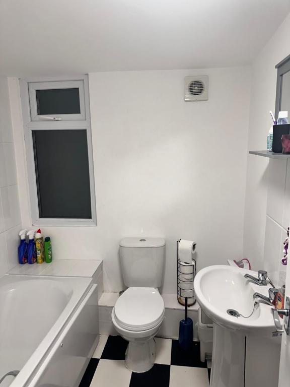 a white bathroom with a toilet and a sink at Rarri place in Manchester