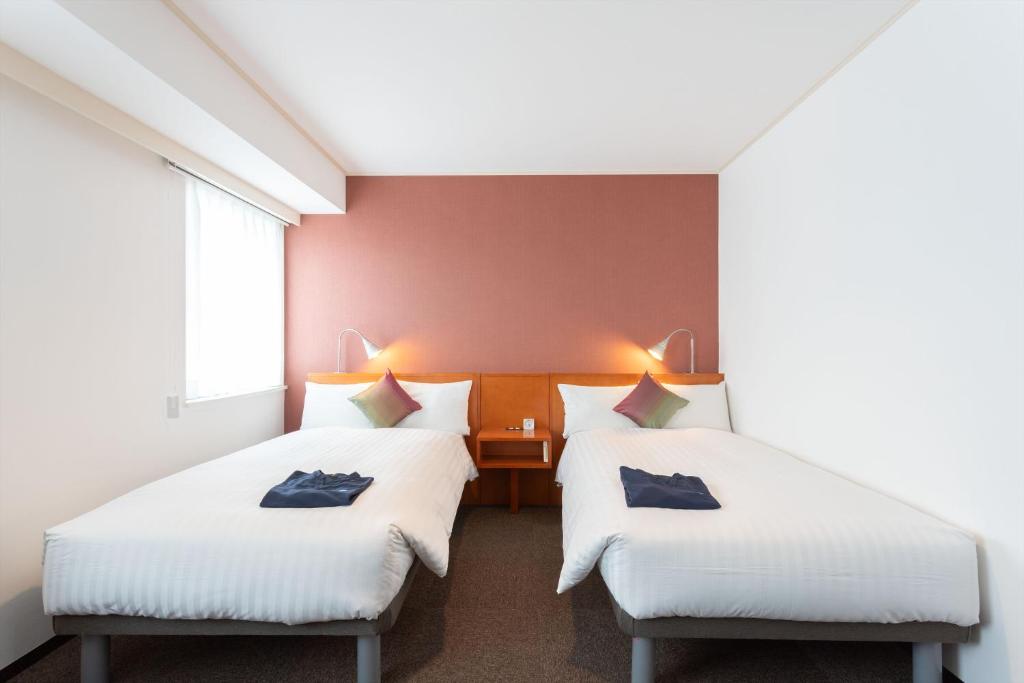 two beds in a room with red walls at Sun Days Kagoshima in Kagoshima