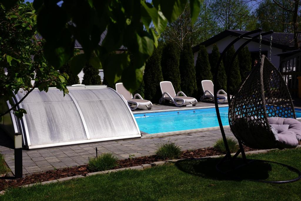 a swimming pool with chairs and a swing next to it at Siedlisko Staszkówka in Huszlew