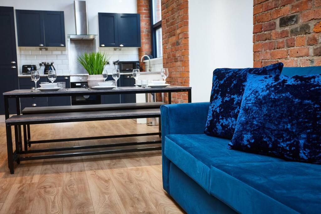 a blue couch in a living room with a kitchen at The Garnet Suite in Manchester