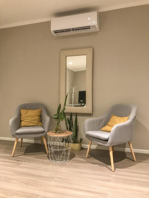 - deux chaises et un miroir dans le salon dans l'établissement Confortabile Apart, à San Fernando del Valle de Catamarca