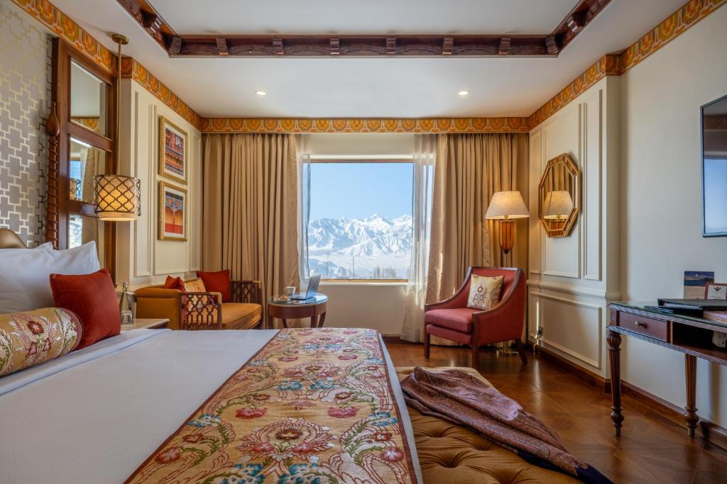 a bedroom with a bed and a desk and a window at The Grand Dragon Ladakh in Leh