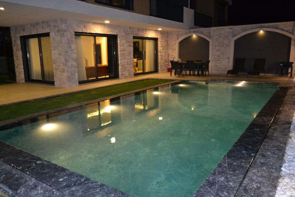 a swimming pool in front of a house at night at çeşme boyalıkta süper lüks in Cesme