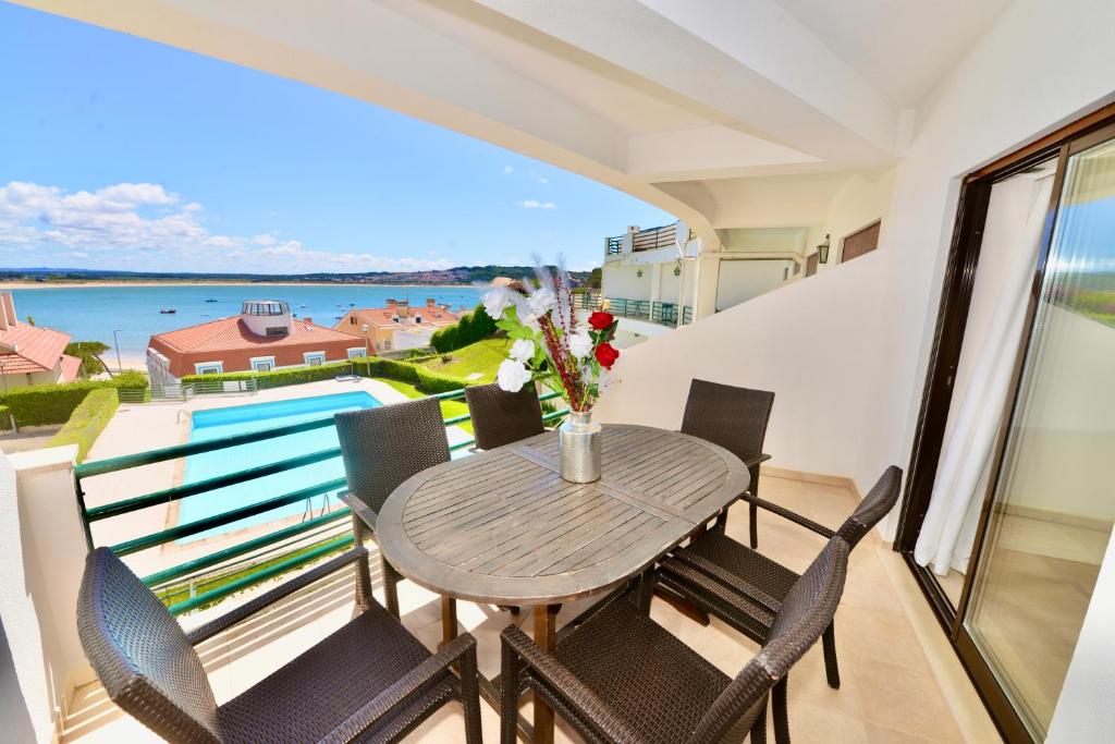 a balcony with a table and chairs and a view of the water at Palm Tree in São Martinho do Porto