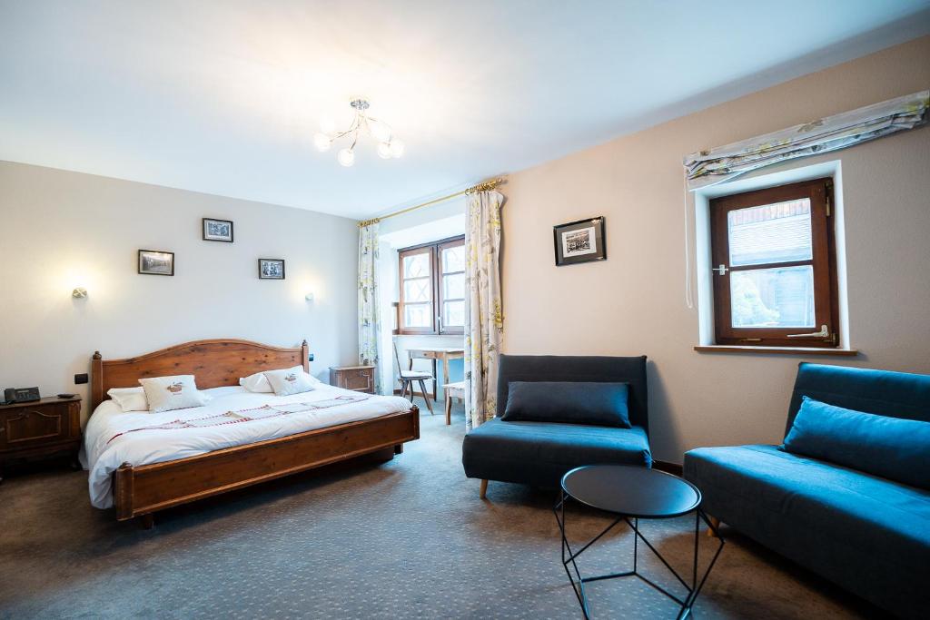 a bedroom with a bed and a couch and a chair at Hôtel Berceau Du Vigneron in Turckheim