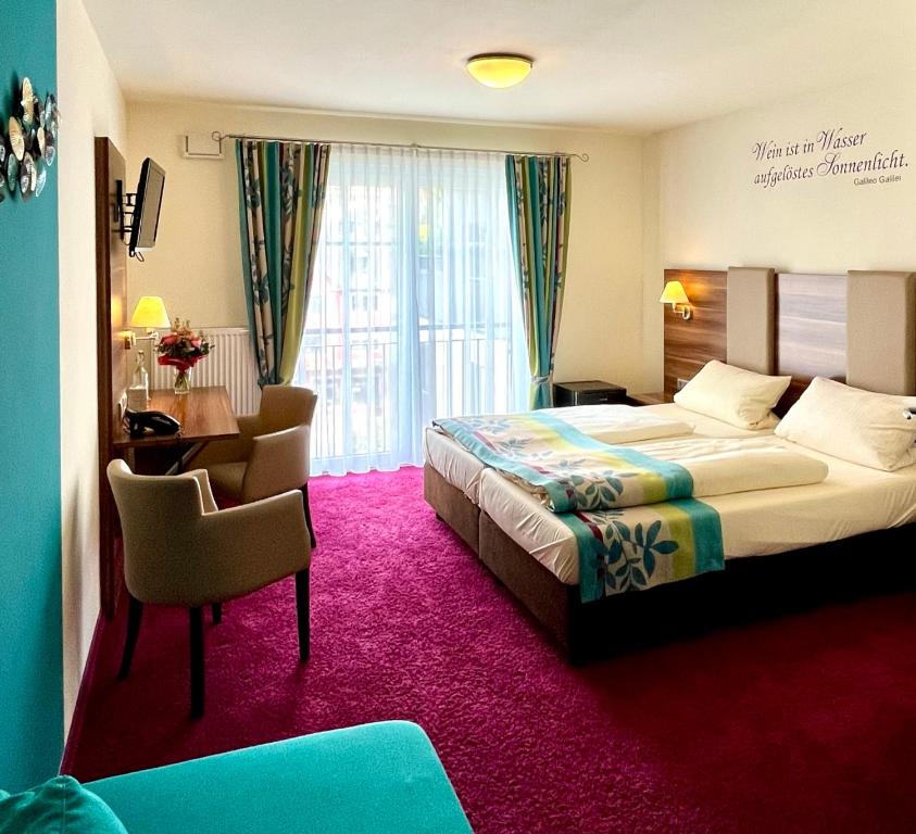 呂德斯海姆的住宿－老德意志葡萄酒吧高級酒店，酒店客房配有一张床铺、一张桌子和一张书桌。