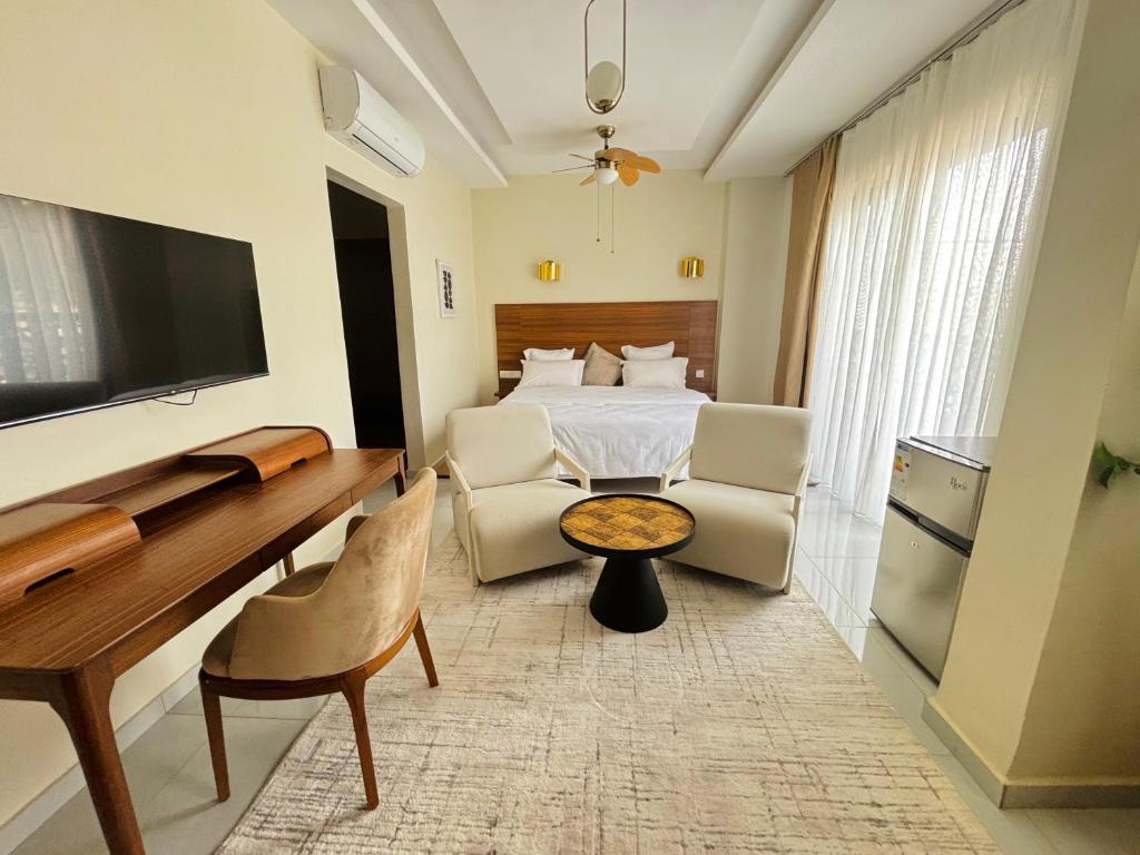 ein Hotelzimmer mit einem Bett, einem Schreibtisch und Stühlen in der Unterkunft Medina Baye Résidence Boutique Hôtel in Kaolack