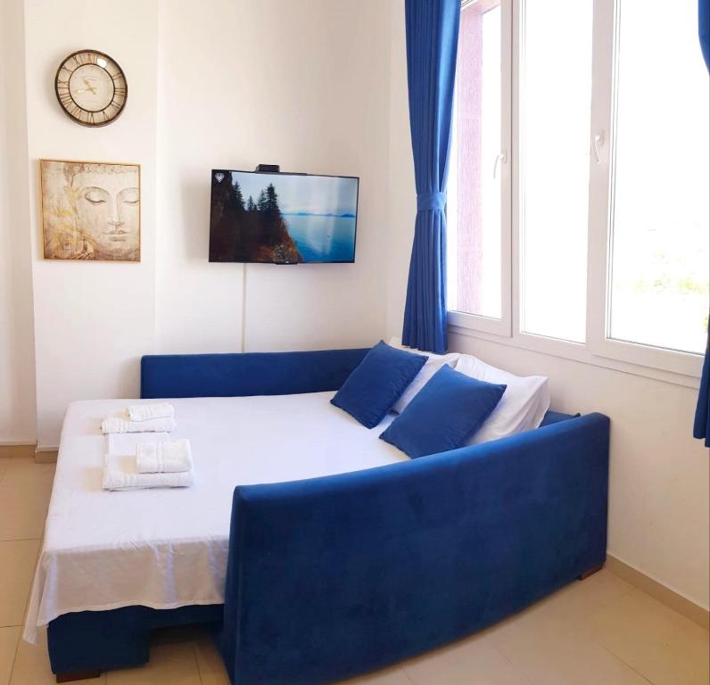 a bedroom with a blue couch and a clock on the wall at Bindi Studio Apartment in Draç