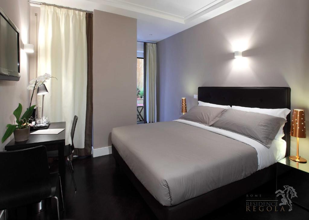 ローマにあるレジデンス レゴラのベッドルーム1室(白いベッド1台、デスク、ベッドサイドシックスシックス付)