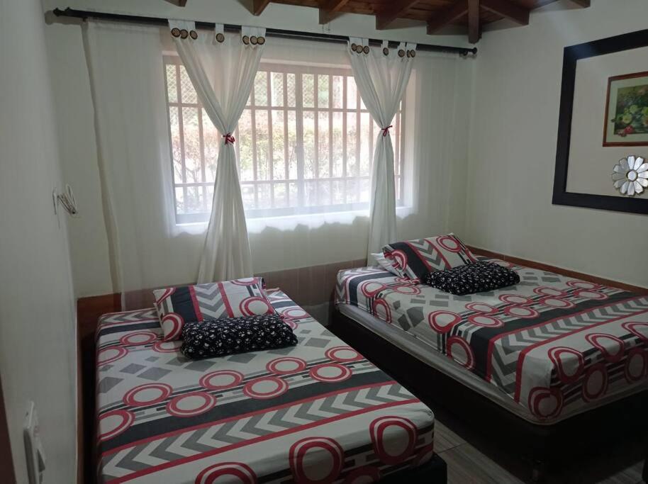 Duas camas num quarto com uma janela em Villa Yolanda em Girardota