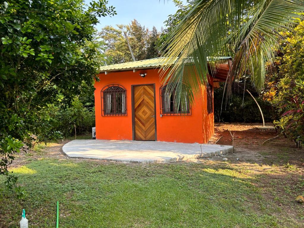 una pequeña casa naranja con una puerta en un patio en Orange Cabina, en Puerto Jiménez