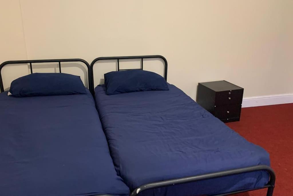1 dormitorio con 2 camas y sábanas azules en Extra large very big Stander bedroom near station in london, en Londres