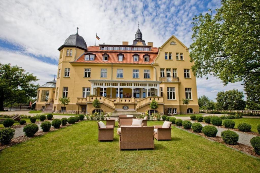 a large yellow building with chairs on a lawn at Bernsteinschloss in Wendorf
