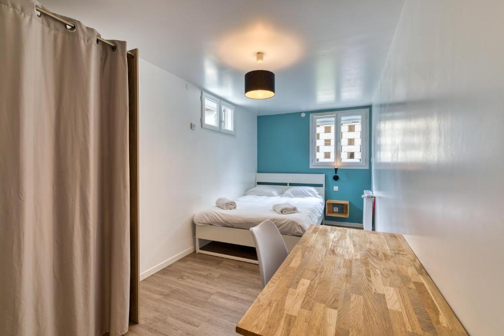 a room with a bed and a wooden table at Céline - Belle Maison moderne in Le Petit-Quevilly