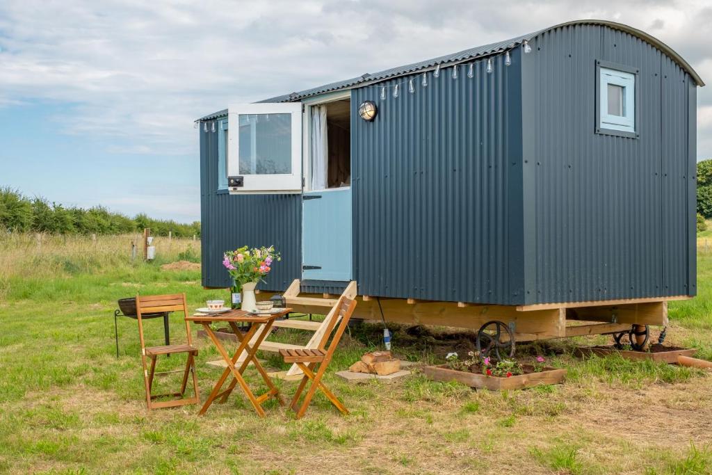 a blue tiny house with a table and chairs at Saltmarsh Hut in Stiffkey
