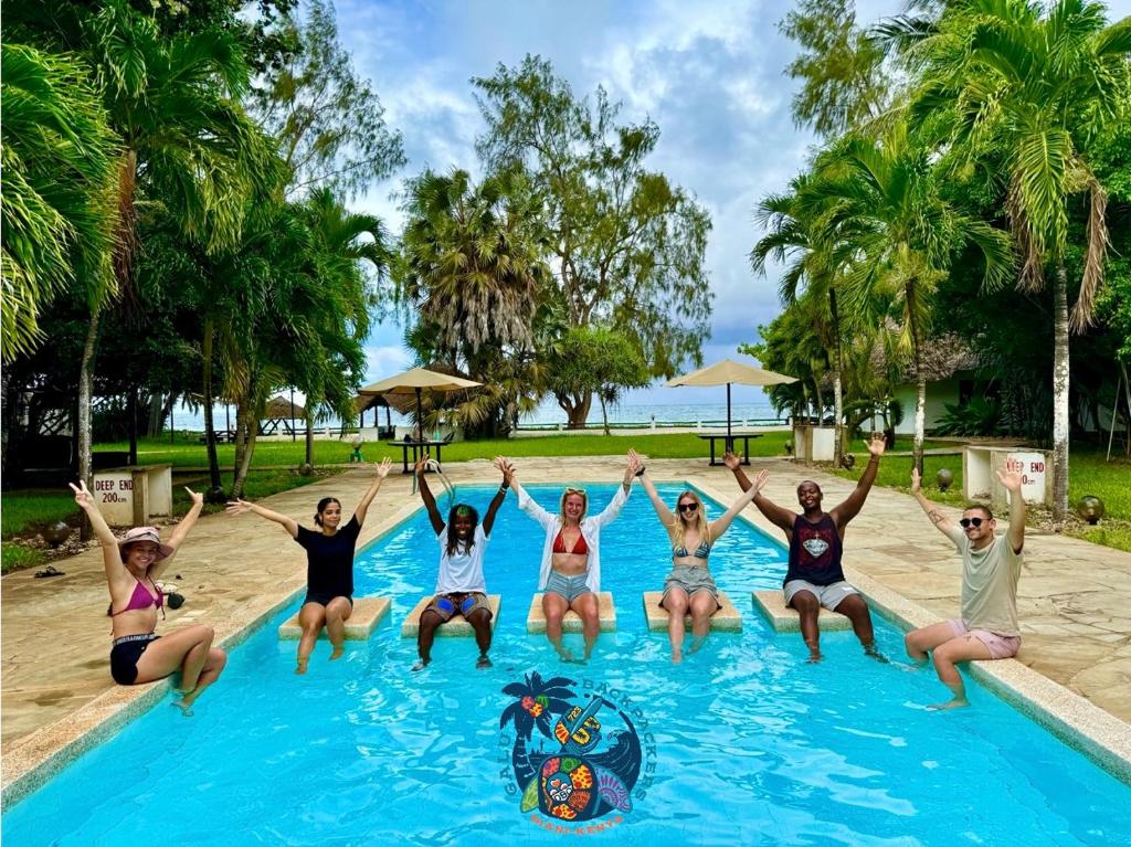 un groupe de personnes assises dans une piscine dans l'établissement Galu Backpackers & Ecolodge, à Diani Beach