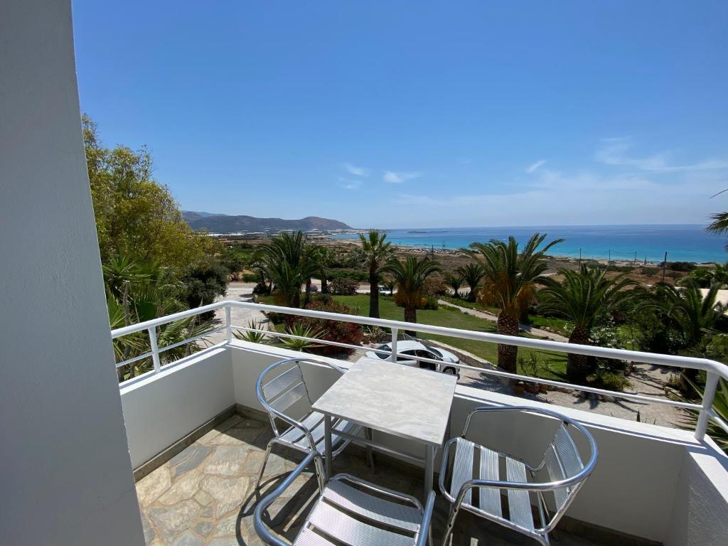 a balcony with a table and chairs and the ocean at Hotel Plakures in Falasarna