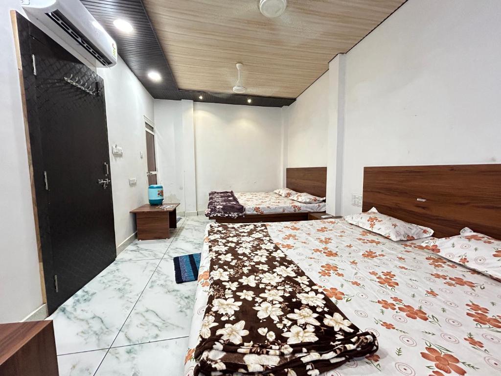 Hotel shree Sidhi vinayak في اوجاين: غرفة نوم بسريرين وتلفزيون على الحائط