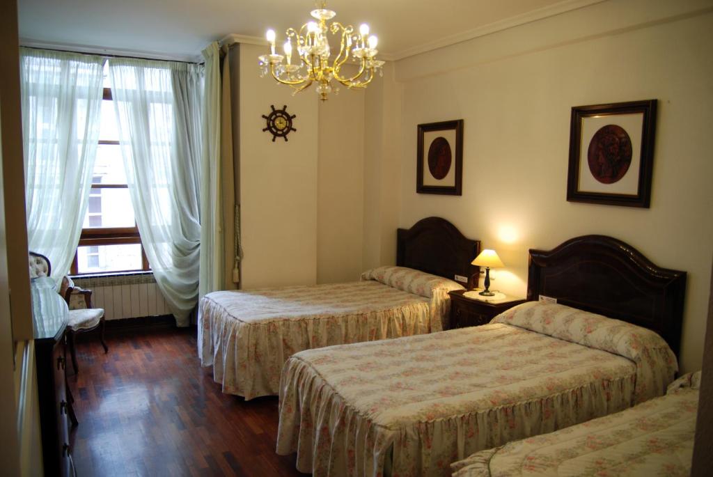 a hotel room with three beds and a chandelier at Pensión Araba II in Vitoria-Gasteiz