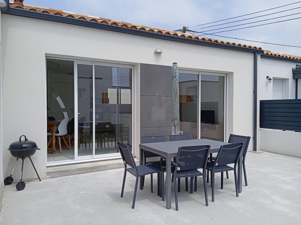 un patio avec une table et des chaises devant une maison dans l'établissement La jolie route des Sables, à Saint-Gilles-Croix-de-Vie