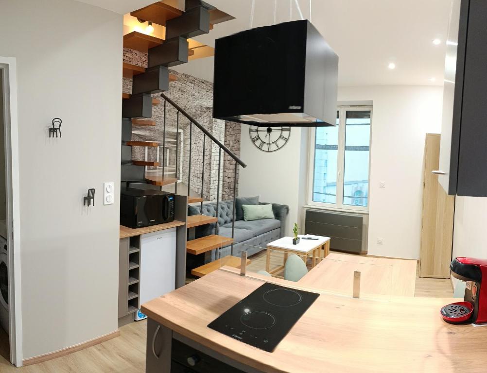 eine Küche und ein Wohnzimmer mit einer Wendeltreppe in der Unterkunft Aux nids douillets Mayetois "les hirondelles" in Mayet-de-Montagne