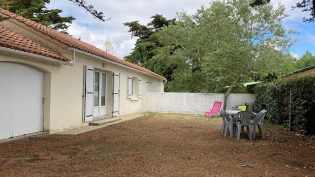 une terrasse avec deux chaises et une table en face d'une maison dans l'établissement La plage de la Pège, à Saint-Hilaire-de-Riez