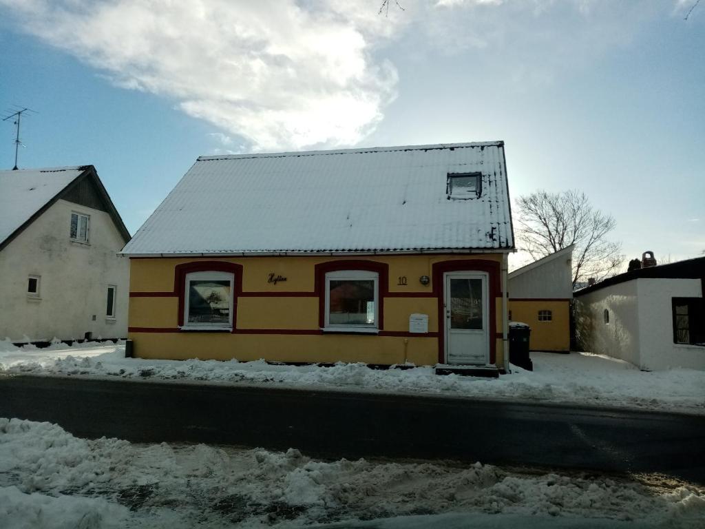 a small yellow house with a snow covered roof at Hytten in Frøstrup
